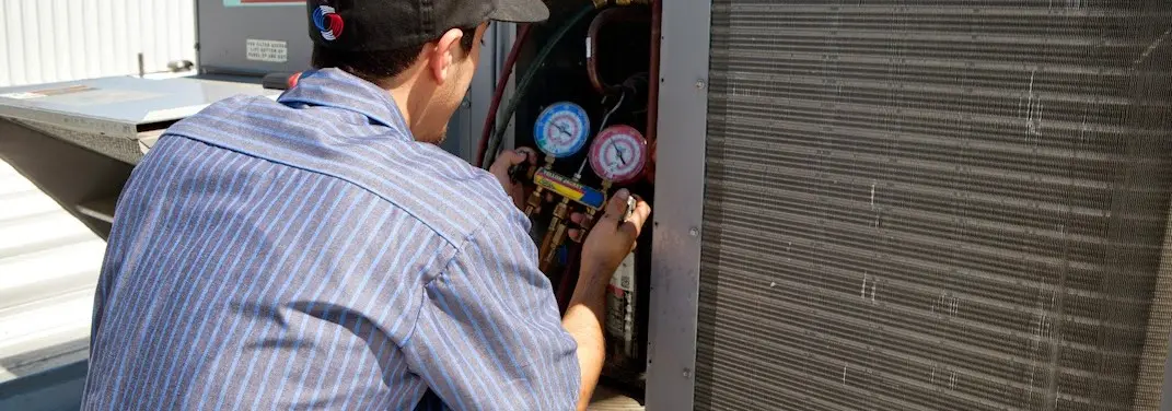 HVAC technician servicing a condenser unit in Williamsville